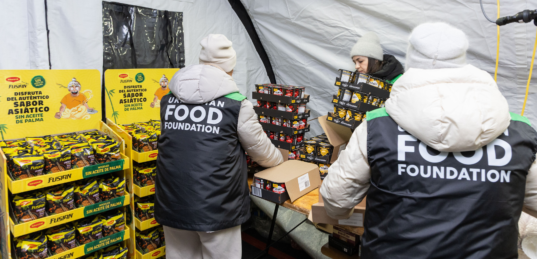 Volunteers from Urban Food Foundation packing instant noodle and snack boxes inside a tent for food distribution.